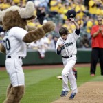 Jake Catterall, 12, of Tacoma, Wash., tips his cap as he heads home and toward the Seattle Mariners' mascot, Mariner Moose, while running a ceremonial run around the bases before the Mariners played their opener against the Los Angeles Angels in a baseball game Monday, April 6, 2015, in Seattle. (AP Photo/Elaine Thompson)