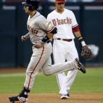 San Francisco Giants' Buster Posey rounds the bases after hitting a two run home run as Arizona Diamondbacks' Jake Lamb, right, looks on during the first inning of a MLB baseball game, Tuesday, April 7, 2015, in Phoenix. (AP Photo/Matt York)