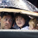 A family takes cover during a rain delay in the MLB All-Star baseball Home Run Derby, Monday, July 14, 2014, in Minneapolis. (AP Photo/Jim Mone)