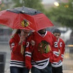 Chicago Blackhawks fans walk through the heavy rain as they arrive at United Center for Game 6 of the NHL hockey Stanley Cup Final between the Chicago Blackhawks and the Tampa Bay Lightning on Monday, June 15, 2015, in Chicago. (AP Photo/Nam Y. Huh)