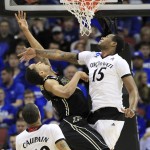 Purdue forward Vince Edwards, left, shoots over Cincinnati forward Jermaine Sanders during the second half of an NCAA tournament second round college basketball game in Louisville, Ky., Thursday, March 19, 2015. Cincinnati won 66-65 in overtime. (AP Photo/David Stephenson)