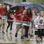 Chicago Blackhawks fans walk through the heavy rain as they arrive at United Center for Game 6 of the NHL hockey Stanley Cup Final between the Chicago Blackhawks and the Tampa Bay Lightning on Monday, June 15, 2015, in Chicago. (AP Photo/Nam Y. Huh)