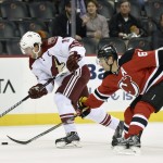 Arizona Coyotes' Shane Doan, left, skates with the puck as New Jersey Devils' Andy Greene attempts a poke check during the first period of an NHL hockey game Monday, Feb. 23, 2015, in Newark, N.J. (AP Photo/Bill Kostroun)