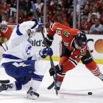 Chicago Blackhawks' Jonathan Toews, right, reaches for a puck after a face-off along side Tampa Bay Lightning's Cedric Paquette during the first period in Game 6 of the NHL hockey Stanley Cup Final series on Monday, June 15, 2015, in Chicago. (AP Photo/Nam Y. Huh)