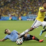 Colombia's Juan Zuniga, right, leaps over Uruguay's Martin Caceres as he loses control of the ball during the World Cup round of 16 soccer match between Colombia and Uruguay at the Maracana Stadium in Rio de Janeiro, Brazil, Saturday, June 28, 2014. (AP Photo/Marcio Jose Sanchez)