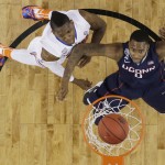 Florida forward Will Yeguete, left, and Connecticut forward Phillip Nolan, right, eye a made basket during the first half of an NCAA Final Four tournament college basketball semifinal game Saturday, April 5, 2014, in Arlington, Texas. (AP Photo/David J. Phillip)