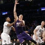 Phoenix Suns' Alex Len (21) drives past Brooklyn Nets' Joe Johnson (7) and Mason Plumlee (1) during the first half of an NBA basketball game Friday, March 6, 2015, in New York. (AP Photo/Frank Franklin II)
