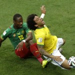 Brazil's Marcelo is tackled by Cameroon's Eyong Enoh during the group A World Cup soccer match between Cameroon and Brazil at the Estadio Nacional in Brasilia, Brazil, Monday, June 23, 2014. (AP Photo/Christophe Ena)