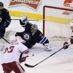 Winnipeg Jets' goaltender Ondrej Pavelec (31) sprawls across the net to try to stop Arizona Coyotes' Oliver Ekman-Larsson (23) and Shane Doan (19) with Jets' Jay Harrison (23) in front of the net during first-period NHL hockey game action in Winnipeg, Manitoba, Sunday, Jan. 18, 2015. (AP Photo/The Canadian Press, Trevor Hagan)