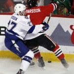 Tampa Bay Lightning's Jonathan Drouin, left, checks Chicago Blackhawks' Niklas Hjalmarsson, of Sweden, into the boards as the chase after a loose puck during the first period in Game 6 of the NHL hockey Stanley Cup Final series on Monday, June 15, 2015, in Chicago. (AP Photo/Charles Rex Arbogast)