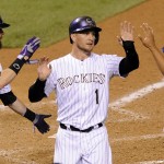 Colorado Rockies' Charlie Blackmon, left, and Cristhian Adames, right, congratulate Brandon Barnes, center, after they scored on a double by Michael Cuddyer in the eighth inning of a baseball game against the Arizona Diamondbacks, Friday, Sept. 19, 2014, in Denver. The Rockies won 15-3. (AP Photo/Chris Schneider)