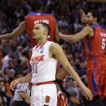  Syracuse's Tyler Ennis (11) walks past as Dayton's Kendall Pollard (22) and Devin Oliver (5) celebrate with teammates during the second half of a third-round game in the NCAA men's college basketball tournament in Buffalo, N.Y., Saturday, March 22, 2014. Dayton won 55-53. (AP Photo/Frank Franklin II)