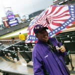 Coors Field security guard Art Mendoza uses an umbrella for cover as a light rain delays the start of the first inning of a baseball game between th Arizona Diamondbacks and Colorado Rockies Monday, May 4, 2015, in Denver. (AP Photo/David Zalubowski)