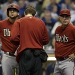 Arizona Diamondbacks' David Peralta, left, gets attention for an injury while batting as manager Chip Hale joins in during the first inning of a baseball game against the Milwaukee Brewers, Sunday, May 31, 2015, in Milwaukee. Peralta left the game. (AP Photo/Jeffrey Phelps)
