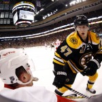 In a photo made with a fish eye lens, Boston Bruins' Torey Krug (47) knocks down Detroit Red Wings' Luke Glendening in the corner during the third period of Boston's 4-1 win in Game 2 of a first-round NHL hockey playoff series in Boston Sunday, April 20, 2014. (AP Photo/Winslow Townson)