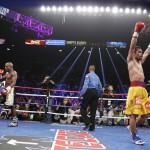 Floyd Mayweather Jr., left, and Manny Pacquiao, right, from the Philippines, return to their corners at the end of their welterweight title fight on Saturday, May 2, 2015 in Las Vegas. At center is referee Kenny Bayless. (AP Photo/John Locher)