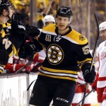 Boston Bruins' Justin Florek is congratulated at the bench after scoring a goal as Detroit Red Wings' Tomas Tatar (21) skates to the bench during the first period of Game 2 of a first-round NHL hockey playoff series in Boston Sunday, April 20, 2014. (AP Photo/Winslow Townson)