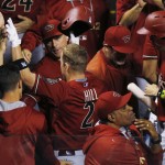 Arizona Diamondbacks third baseman Aaron Hill, center, is congratulated by teammates after hitting a sacrifice fly to bring in the go-ahead run off Colorado Rockies relief pitcher John Axford in the ninth inning of a baseball game Wednesday, June 24, 2015, in Denver. Arizona won 8-7. (AP Photo/David Zalubowski)
