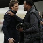 New England Patriots quarterback Tom Brady, left, is greeted by former Patriots' Willie McGinest as he arrives at Sky Harbor Airport for NFL Super Bowl XLIX football game against the Seattle Seahawks Monday, Jan. 26, 2015, in Phoenix. (AP Photo/Charlie Riedel)

