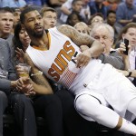 Phoenix Suns' Marcus Morris lands in the front row of fans and and sends beer flying as he jumped to save a ball from going out of bounds during the second half of an NBA basketball game against the Miami Heat, Tuesday, Dec. 9, 2014, in Phoenix. The Heat won 103-97. (AP Photo/Ross D. Franklin)