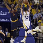 Cleveland Cavaliers guard J.R. Smith (5) defends as Golden State Warriors guard Stephen Curry (30) shoots during the first half of Game 5 of basketball's NBA Finals in Oakland, Calif., Sunday, June 14, 2015. (AP Photo/Ben Margot)
