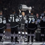 Los Angeles Kings right wing Dustin Brown, center, raises the Stanley Cup before the Stanley Cup Championship banner is revealed prior to an NHL hockey game against the San Jose Sharks, Wednesday, Oct. 8, 2014, in Los Angeles. (AP Photo/Mark J. Terrill)