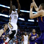 New Orleans Pelicans guard Jrue Holiday (11) goes to the basket against Phoenix Suns center Alex Len, right, and guard Goran Dragic, left, during the second half of an NBA basketball game, Tuesday, Dec. 30, 2014, in New Orleans. The Pelicans won 110-106. (AP Photo/Jonathan Bachman)