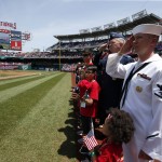  U.S. Navy Hospitalman Third Class Johnathan Loper, right, and others salute during the National Anthem before a baseball game between the Washington Nationals and the Miami Marlins at Nationals Park, on Memorial Day, Monday, May 26, 2014, in Washington. (AP Photo/Alex Brandon)