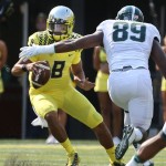
Oregon quarterback Marcus Mariota, left, is flushed out of the pocket by Michigan State's Shilique Calhoun during the first quarter of their college football game in Eugene, Oregon, Saturday Sept. 6, 2014. (AP Photo/Chris Pietsch)