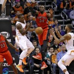 Phoenix Suns' Eric Bledsoe, center, dishes off to Marcus Morris (15) as Toronto Raptors' Patrick Patterson (54) and Lou Williams (23) defend during the first half of an NBA basketball game, Sunday, Jan. 4, 2015, in Phoenix. (AP Photo/Matt York)