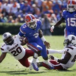 Florida quarterback Treon Harris (3) runs for yardage between South Carolina safety T.J. Gurley (20) and linebacker Skai Moore (10) during the first half of an NCAA college football game in Gainesville, Fla., Saturday, Nov. 15, 2014. (AP Photo/John Raoux) 