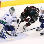 Vancouver Canucks' Eddie Lack (31) makes a save on a shot by Arizona Coyotes' Tye McGinn (20) as Canucks' Yannick Weber (6), of Switzerland, defends during the second period of an NHL hockey game Thursday, March 5, 2015, in Glendale, Ariz. (AP Photo/Ross D. Franklin)