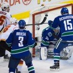 Vancouver Canucks' Brad Richardson (15) swats the puck away from Calgary Flames' Josh Jooris (86) and Joe Colborne (8) in front of goalie Ryan Miller as Kevin Bieksa (3) watches during the second period of Game 5 of an NHL hockey first-round playoff series, Thursday, April 23, 2015, in Vancouver, British Columbia. (Darryl Dyck/The Canadian Press via AP)
