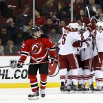  New Jersey Devils ring wing Damien Brunner (12), of the Czech Republic, skates away as members of the Phoenix Coyotes celebrate a goal by Chris Summers during the second period of an NHL hockey game, Thursday, March 27, 2014, in Newark, N.J. (AP Photo/Julio Cortez)
