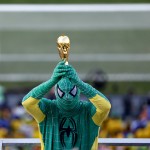 A person in a Spiderman costume, in the colors of Brazil's flag, holds up a replica of the World Cup trophy before the start of the opening match between Brazil and Croatia at Itaquerao Stadium in Sao Paulo, Brazil, Thursday, June 12, 2014. Thursday is a holiday in Sao Paulo and everybody is celebrating the start of the international soccer tournament. (AP Photo/Julio Cortez