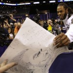 Seattle Seahawks' Richard Sherman is handed a drawing during media day for NFL Super Bowl XLIX football game Tuesday, Jan. 27, 2015, in Phoenix. (AP Photo/David J. Phillip)
