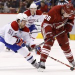Montreal Canadiens' David Desharnais (51) reaches between the legs of Arizona Coyotes' Michael Stone (26) to control the puck during the first period of an NHL hockey game Saturday, March 7, 2015, in Glendale, Ariz. (AP Photo/Ross D. Franklin)
