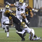 Arizona State running back Kalen Ballage is tackled by UCLA defensive back Ishmael Adams, right, as defensive lineman Eddie Vanderdoes (47) pursues during the first half of an NCAA college football game, Thursday, Sept. 25, 2014, in Tempe, Ariz. (AP Photo/Rick Scuteri)