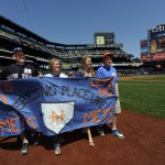 Scott Kurczeski, wife Carol, son, Jeff, right, and friend Maggie Allen of Freehold, New Jersey display walk the warning track with their banner on Banner Day before the baseball game at Citi Field on Sunday, May 25, 2014, in New York. (AP Photo/Kathy Kmonicek)