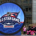 Hockey fans pose with a giant hockey puck outside Nationwide Arena, Saturday, Jan. 24, 2015 in Columbus, Ohio. The NHL All-Star hockey game will be played Sunday at the arena. (AP Photo/Gene J. Puskar)
