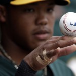 Oakland Athletics shortstop Addison Russell rolls a baseball on his hand in the dugout as the Athletics play the Arizona Diamondbacks in an exhibition spring training baseball game Thursday, March 6, 2014, in Scottsdale, Ariz. (AP Photo/Gregory Bull)