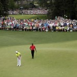 Tiger Woods, right, watches as Rory McIlroy, of Northern Ireland, putts on the fifth green during the fourth round of the Masters golf tournament Sunday, April 12, 2015, in Augusta, Ga. (AP Photo/Charlie Riedel)