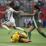 United States' Alex Morgan jumps over Nigeria goalkeeper Precious Dede as Nigeria's Onome Ebi watches during the first half of a FIFA Women's World Cup soccer game Tuesday, June 16, 2105, in Vancouver, British Columbia, Canada. (Jonathan Hayward/The Canadian Press via AP)
