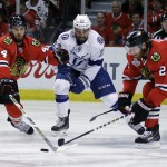 Chicago Blackhawks' Niklas Hjalmarsson, of Sweden, and Duncan Keith, right, reach for a loose puck along side Tampa Bay Lightning's J.T. Brown, center, during the first period in Game 6 of the NHL hockey Stanley Cup Final series on Monday, June 15, 2015, in Chicago. (AP Photo/Nam Y. Huh)