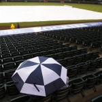 A lone fan seeks cover under an umbrella as a light rain delays the start of the first inning of a baseball game between the Arizona Diamondbacks and the Colorado Rockies Monday, May 4, 2015, in Denver. (AP Photo/David Zalubowski)