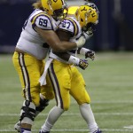 LSU guard Hoko Fanaika (69) hugs running back Kenny Hilliard (27) after Hilliard rushed for a first down to seal a victory against Wisconsin during the second half of an NCAA college football game Saturday, Aug. 30, 2014, in Houston. LSU won 28-24. (AP Photo/David J. Phillip)
