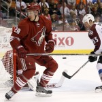 Arizona Coyotes' Michael Stone (26) looks for the puck as Colorado Avalanche's Cody McLeod (55) tries to get a stick on the puck during the first period of an NHL hockey game Tuesday, Nov. 25, 2014, in Glendale, Ariz. (AP Photo/Ross D. Franklin)