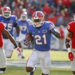 Florida running back Kelvin Taylor (21) runs for yardage past Georgia cornerback Devin Bowman (37) and safety Quincy Mauger (20) during the first half of an NCAA college football game in Jacksonville, Fla., Saturday, Nov. 1, 2014. (AP Photo/Stephen B. Morton)