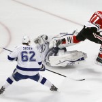 Chicago Blackhawks' Andrew Desjardins, right, flies over Tampa Bay Lightning goalie Ben Bishop, center, while chasing after a loose puck as Lightning's Andrej Sustr, of the Czech Republic, watches during the second period in Game 6 of the NHL hockey Stanley Cup Final series on Monday, June 15, 2015, in Chicago. (AP Photo/Charles Rex Arbogast)