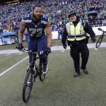 Seattle Seahawks' Michael Bennett borrows a police officers bike after overtime of the NFL football NFC Championship game against the Green Bay Packers Sunday, Jan. 18, 2015, in Seattle. The Seahawks won 28-22 to advance to Super Bowl XLIX. (AP Photo/David J. Phillip)